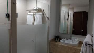 Un baño moderno con cabina de ducha de vidrio, un lavamanos con espejo y un perchero para toallas.