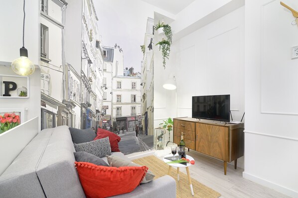 A modern living room with a sofa, a wooden cabinet, and a television. - R&R Apart Cracow (Kraków)
