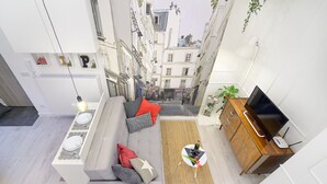 A modern living room with a sofa, a dining table, and a TV. - R&R Apart Cracow (Kraków)