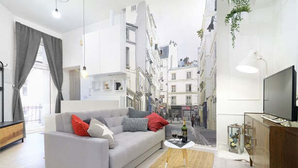 A modern living room with a grey sofa, red and grey cushions, a small white table with a bottle and glasses, and a TV on a wooden cabinet. - R&R Apart Cracow (Kraków)