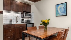 Una cucina moderna con mobili in legno scuro, un forno a microonde in acciaio inossidabile e un tavolo da pranzo con sedie.
