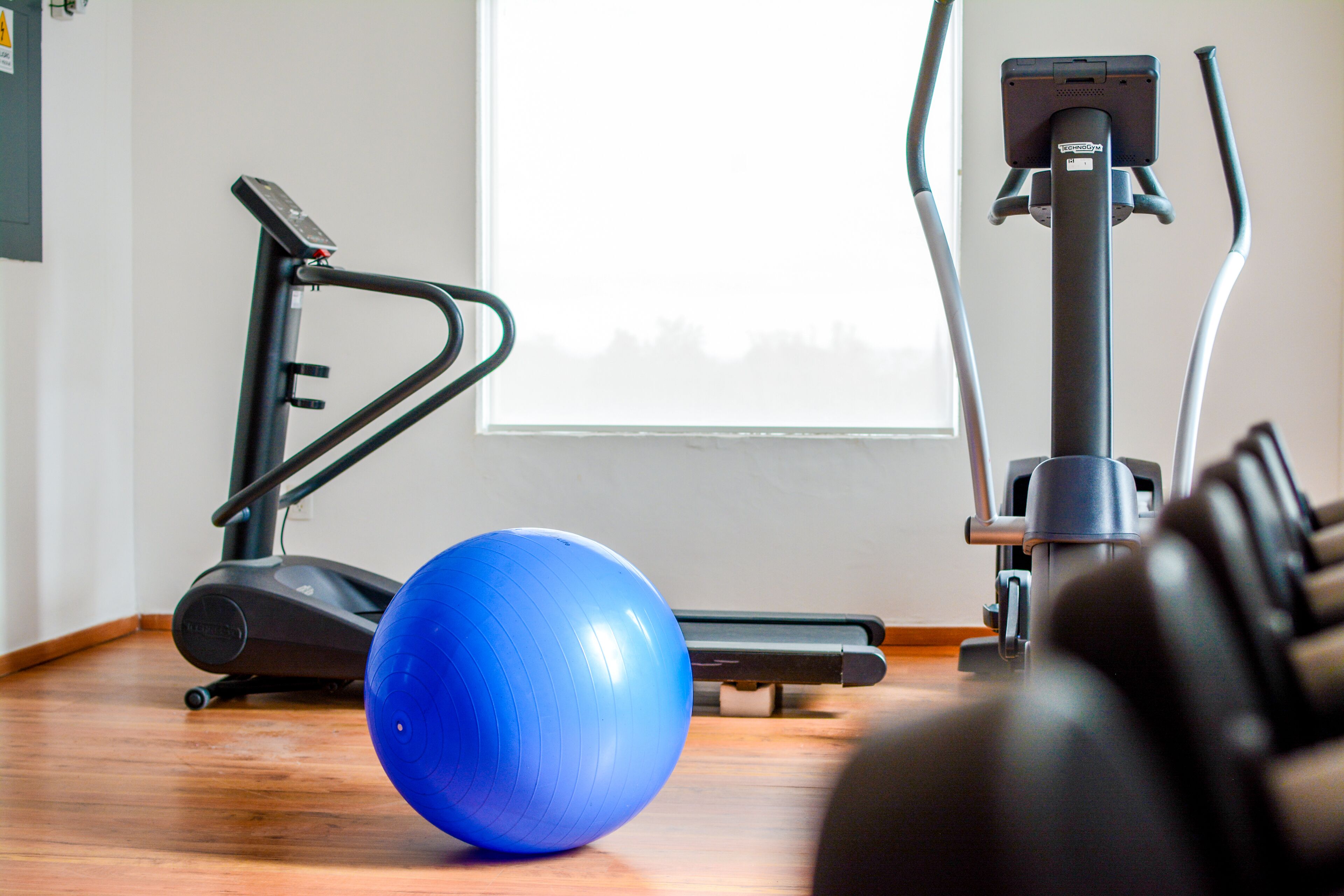 Una palestra in casa con una cyclette, un ellittico e una palla ginnastica blu.
