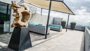 Terraza en la azotea con una escultura moderna, zona de estar y plantas en macetas.