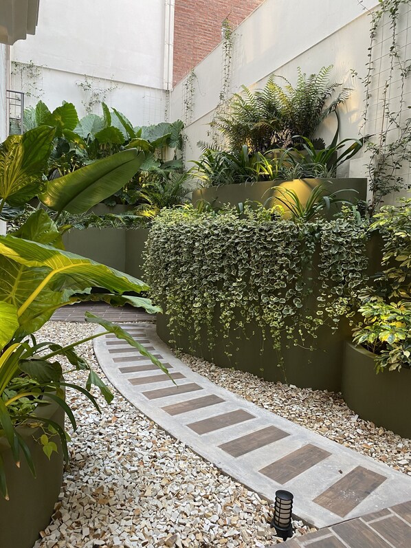 Un espace jardin aménagé avec un chemin de gravier, différentes plantes et un mur en briques.