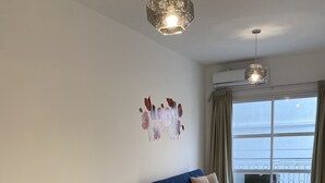 Ein modernes Wohnzimmer mit einem Glastisch, weißen Stühlen, einem blauen Sofa und einem Wandbild.