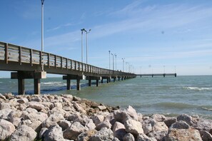 Un muelle que se adentra en el agua, con una costa rocosa al frente.