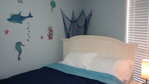 A bedroom with a bed, a wall decoration of sea creatures, and a window with blinds. - Beach Condo Walk to the sand beach and Texas State Aquarium. (Corpus Christi)