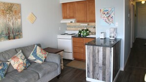 A compact kitchen with wooden cabinets, a white stove, and a coffee maker. - Beach Condo Walk to the sand beach and Texas State Aquarium. (Corpus Christi)