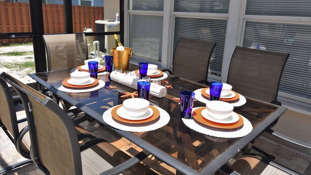 A dining table set with white plates, blue glasses, and a gold centerpiece. - Arlington Park Area! Heated Pool 3 bedroom/ 2 bath (Sarasota)