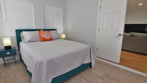 A bedroom with a bed, nightstands, and a door leading to a bathroom. - Arlington Park Area! Heated Pool 3 bedroom/ 2 bath (Sarasota)