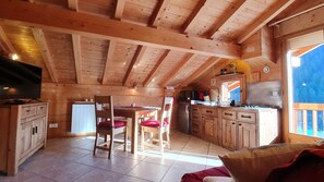 Un intérieur de chalet chaleureux comprenant un coin repas, une cuisine et un téléviseur.