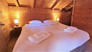 Une chambre de style cabane en bois, avec un lit, deux lampes de chevet et des serviettes sur le lit.