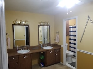 A bathroom with two sinks, a mirror, a towel rack, and a shower curtain.