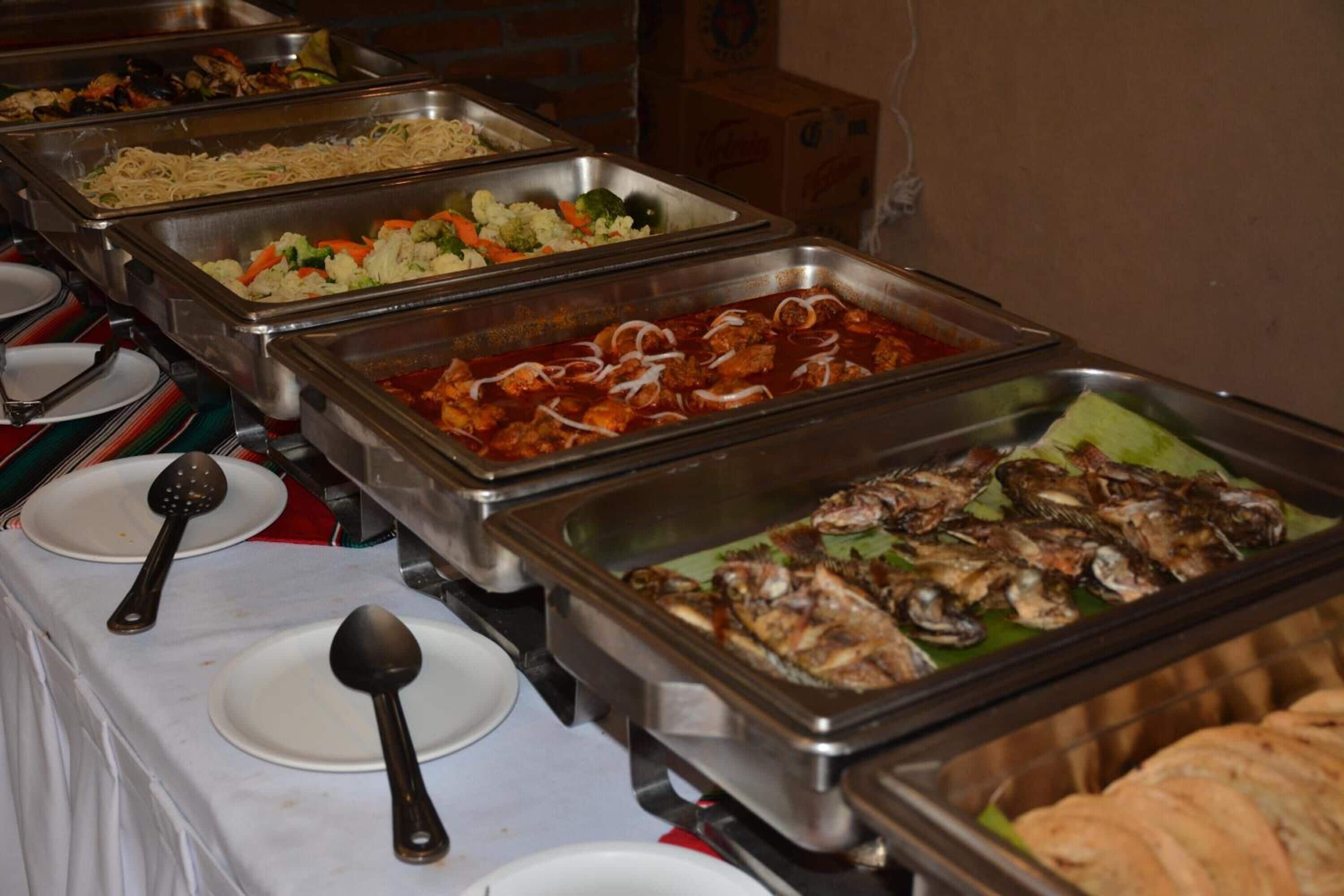 Un buffet proposant une variété de plats, notamment des pâtes, des légumes, de la viande et du poisson.