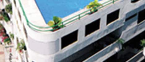 A multi-story hotel with a rooftop pool area featuring sun loungers and umbrellas.