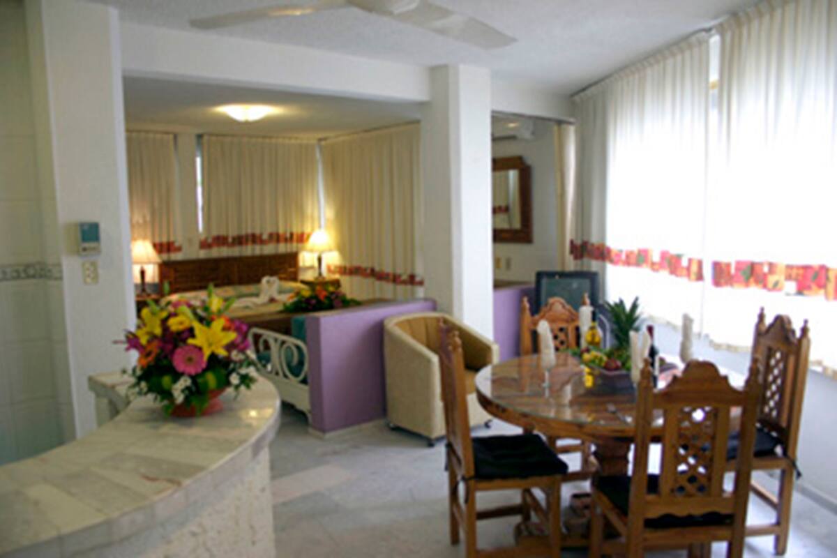 Ein Hotelzimmer mit Essbereich, einer Sitzecke und einem durchgegangenen Badezimmer.