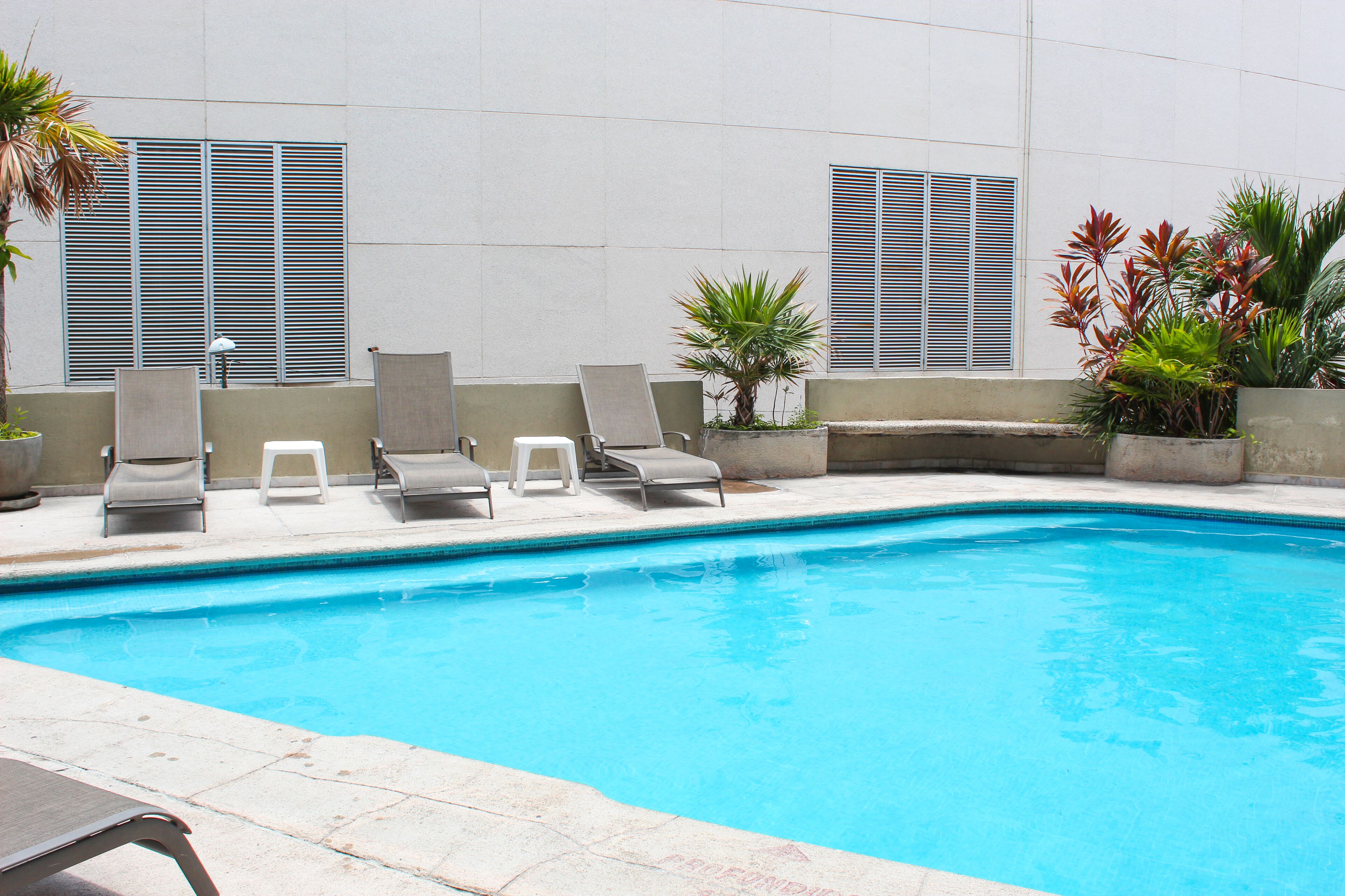 A swimming pool with lounge chairs and potted plants.