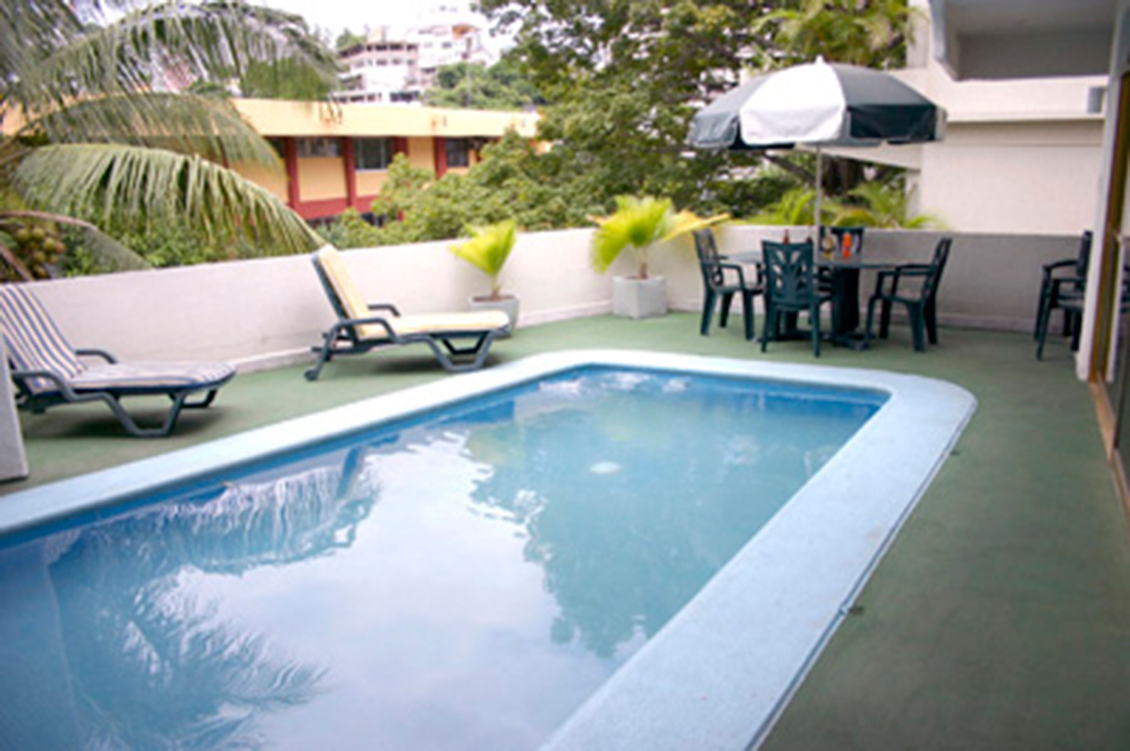 A swimming pool with lounge chairs and a table with umbrellas.