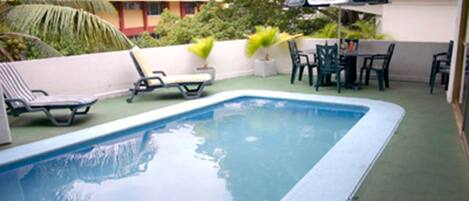 A swimming pool with lounge chairs and a table with umbrellas.