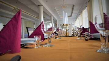 Una mesa de comedor formal decorada con cristalería transparente, platos blancos y candelabros dorados.