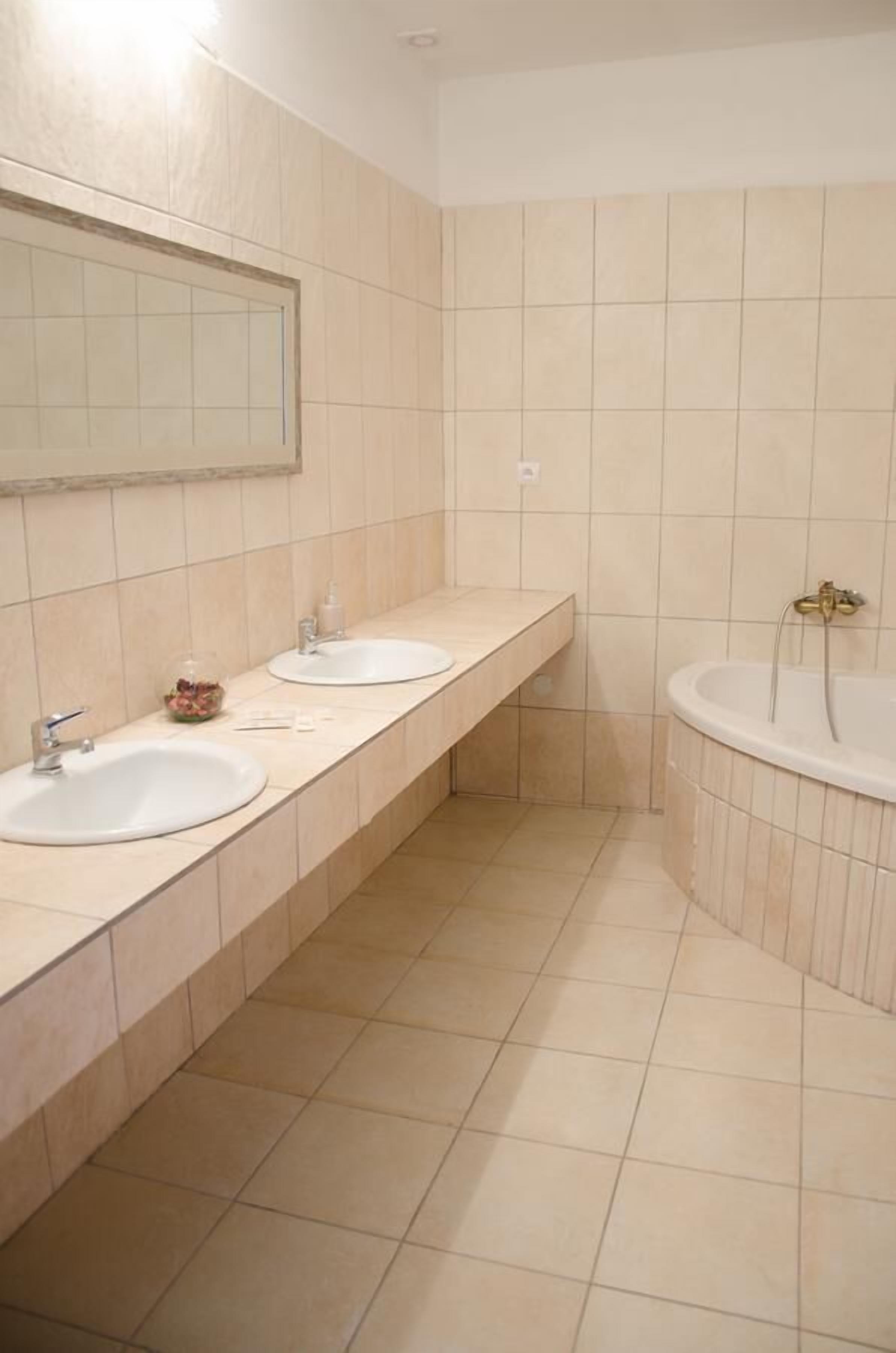 A bathroom with two sinks, a mirror, and a bathtub.