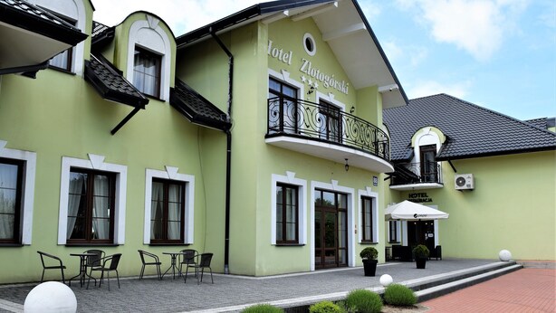 A green building with a balcony, outdoor seating, and a sign that reads "Hotel Zlotogorski". - Hotel Zlotogorski (gmina Koscielec)