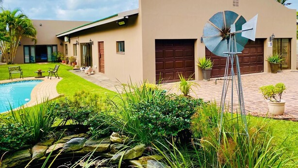 A modern house with a swimming pool, a windmill, and a well-maintained garden. - Rooibos Retreat (Richards Bay)