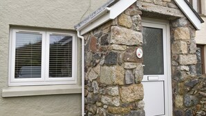 Una casa de piedra con una puerta blanca y contraventanas.