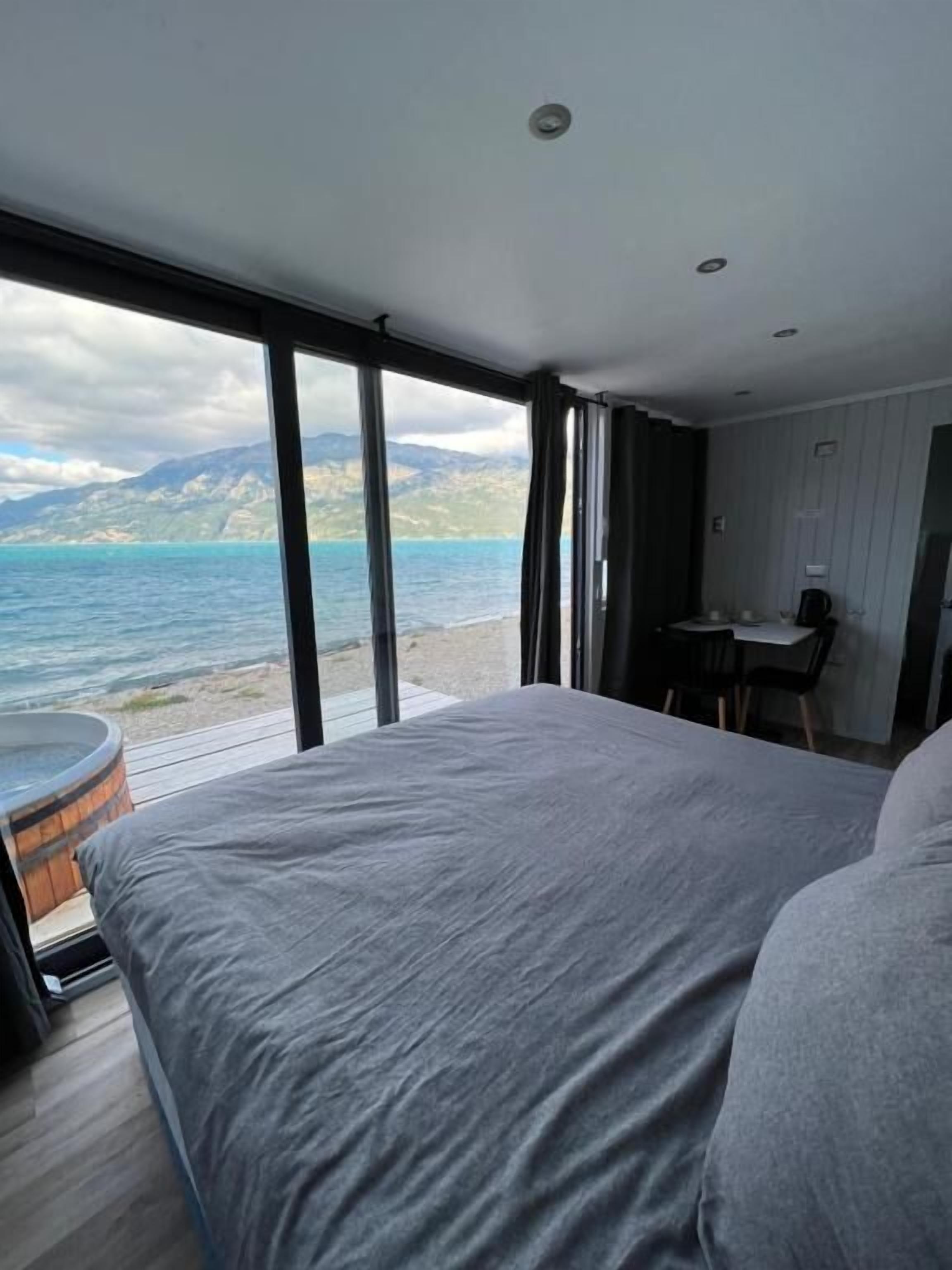 Un dormitorio con una cama grande, un escritorio y vista al mar.