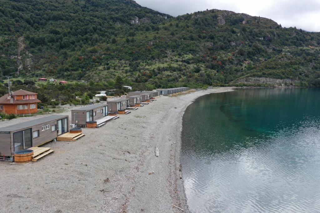 A row of cabins with a beach and mountains in the background.