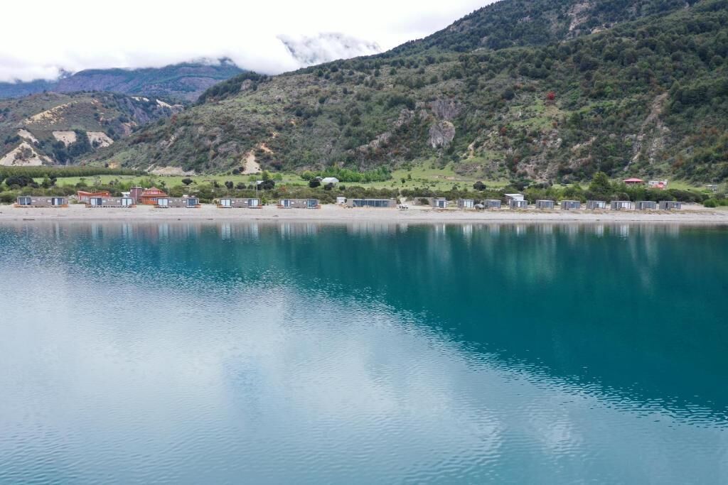A coastal hotel with a view of a calm lake and mountains in the background.