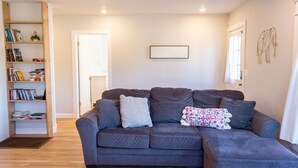 A living room with a grey sofa, a bookshelf, and a framed quote on the wall. - Blue Cottage in the heart of Tulsa (Tulsa)