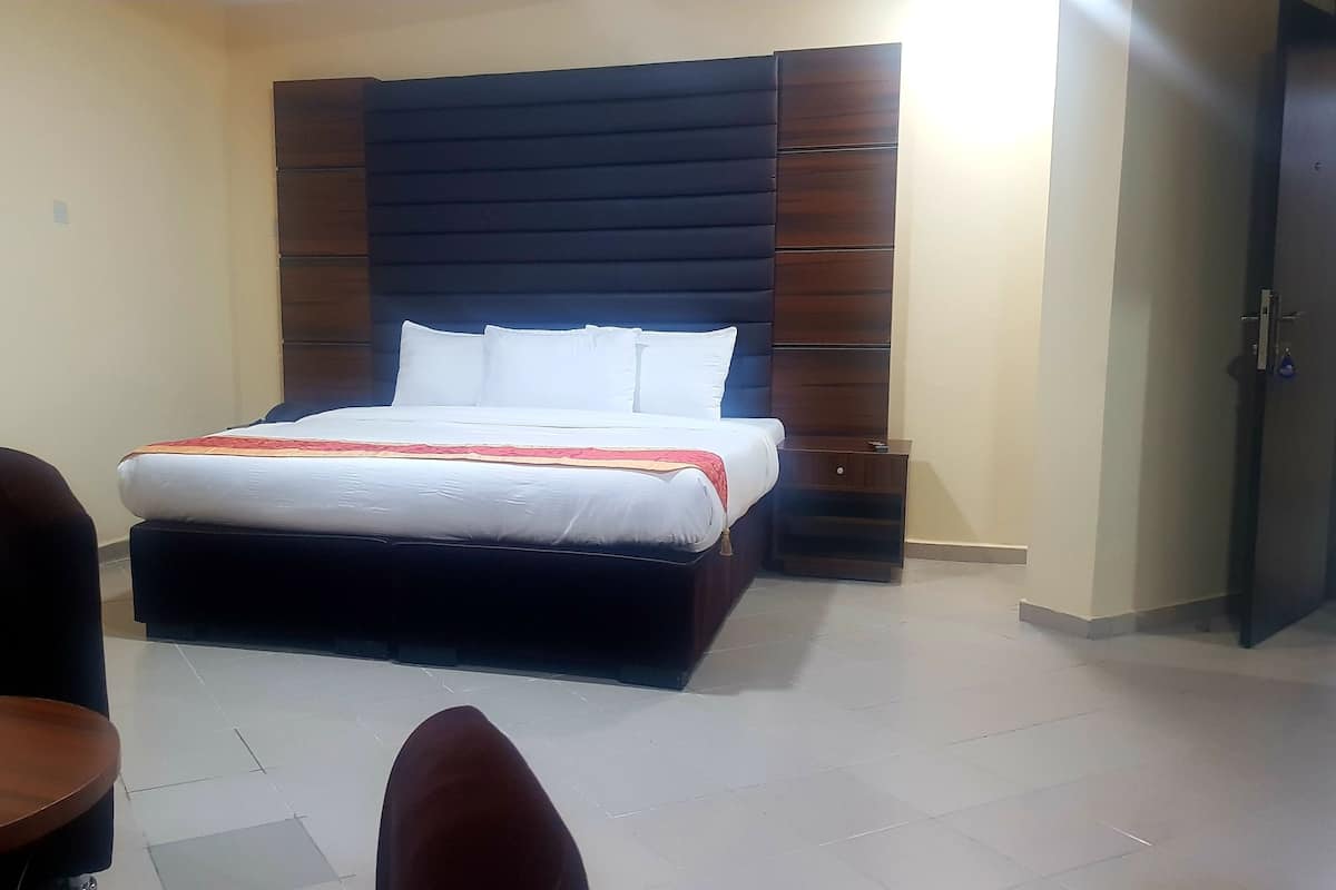 A hotel room with a bed, a chair, a small table, and a wardrobe.