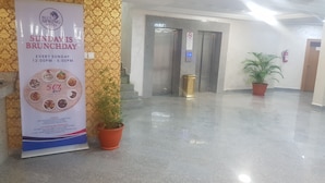 A hotel lobby with a sign promoting Sunday brunch, a fire extinguisher, and a potted plant. - Blue Springs Hotel (Abuja)