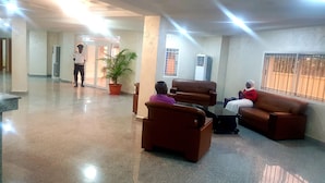 A lobby with seating areas, a reception desk, and a security guard. - Blue Springs Hotel (Abuja)