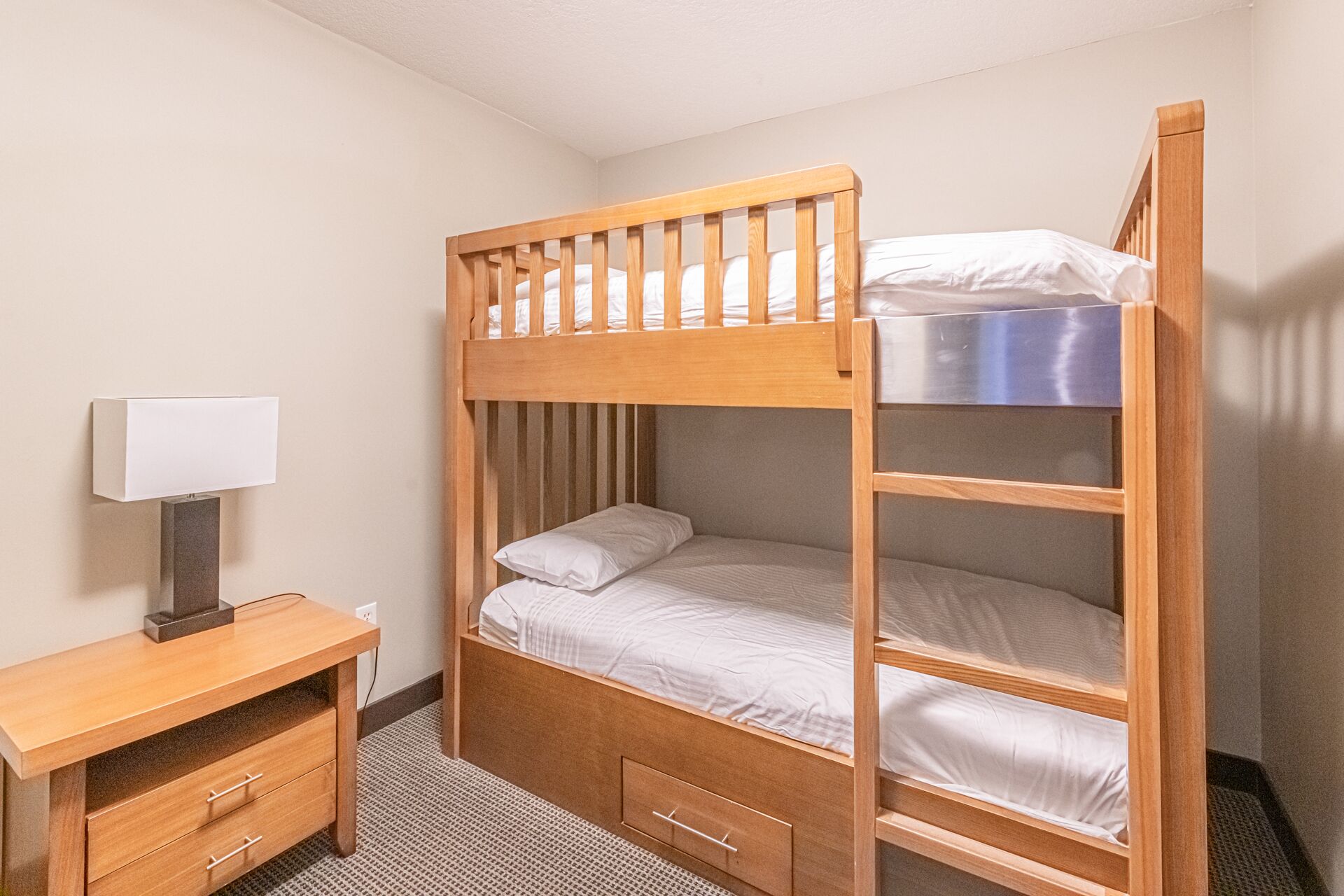 A bunk bed room with a desk and a lamp.