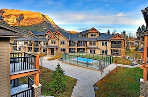Un complejo residencial con varias casas de dos pisos, una piscina comunitaria y montañas al fondo.