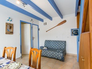 Una habitación con una mesa de comedor de madera, dos sillas, un sofá y un ventilador de techo.