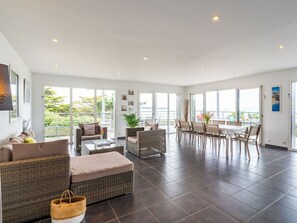 Relax in a spacious living area with expansive views of the surrounding landscape, featuring a comfortable seating arrangement and dining table.