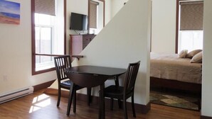 A room with a dining table, chairs, a bed, a TV, and a staircase. - Water Suites (Charlottetown)