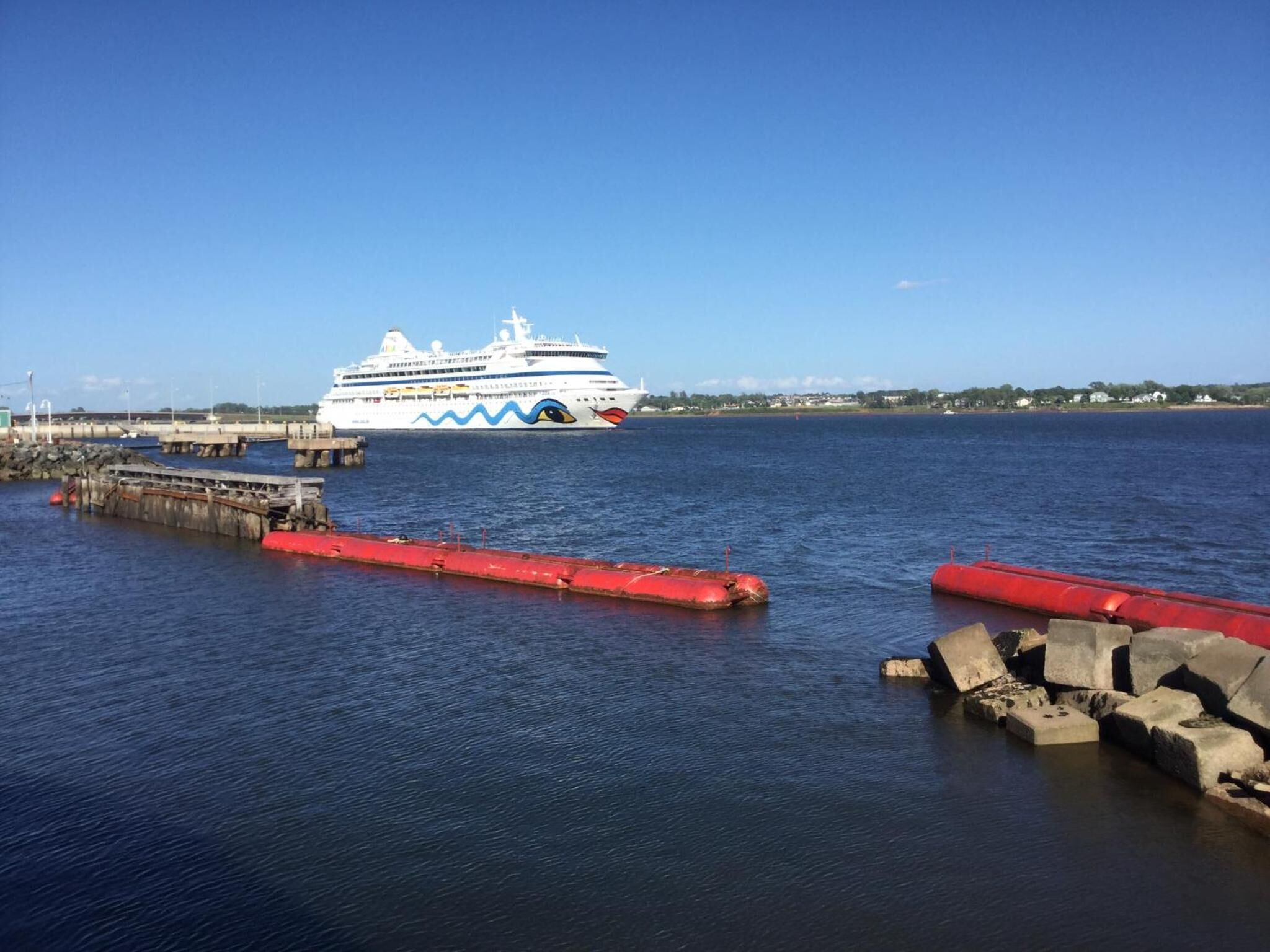 Een cruiseschip aangemeerd aan een steiger, met een helderblauwe lucht.