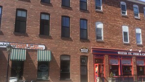 A brick building with storefronts including a coffee shop, a restaurant, and a seafood restaurant. - Water Suites (Charlottetown)