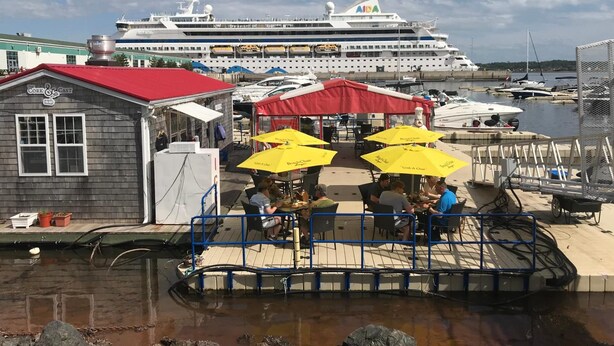 A waterfront dock with a small building labeled "The Cork & Cast" and a large cruise ship docked in the background. - Water Suites (Charlottetown)