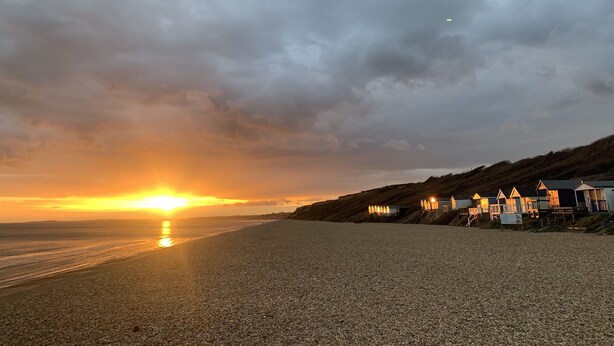 A beach with pebbles and a row of houses with steps leading down to the beach. - Beautiful, stylish New Forest 2 bed cottage, close to the beach! (Lymington)