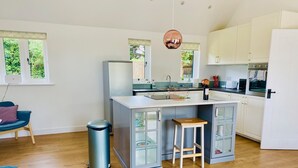 A modern kitchen with a central island, white cabinetry, and a hanging pendant light. - Beautiful, stylish New Forest 2 bed cottage, close to the beach! (Lymington)