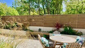 An outdoor patio with a round wooden table and four wooden chairs with floral cushions. - Beautiful, stylish New Forest 2 bed cottage, close to the beach! (Lymington)