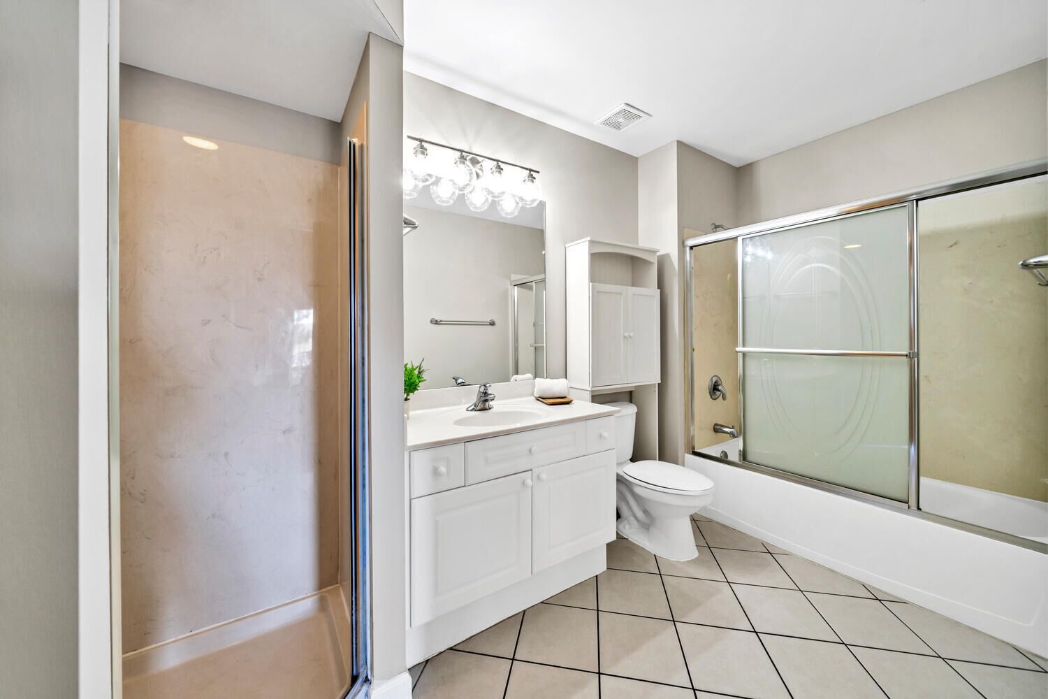A modern bathroom with a glass-enclosed shower, white fixtures, and a tiled floor.