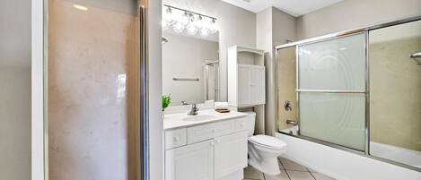 A modern bathroom with a glass-enclosed shower, white fixtures, and a tiled floor.
