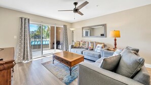 A living room with a sofa, coffee table, and a ceiling fan. - Amalfi Coast - Spacious Condo! (Miramar Beach)
