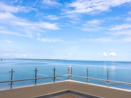 Un balcón con baranda de metal que da a un mar tranquilo bajo un cielo despejado.